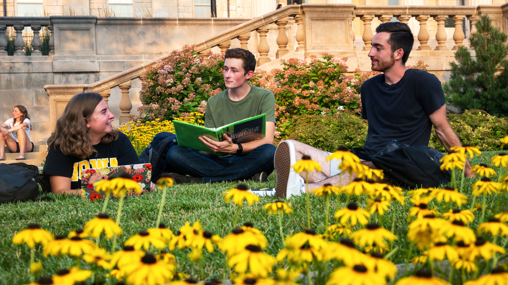 Students sitting in the grass amongst flowers. 
