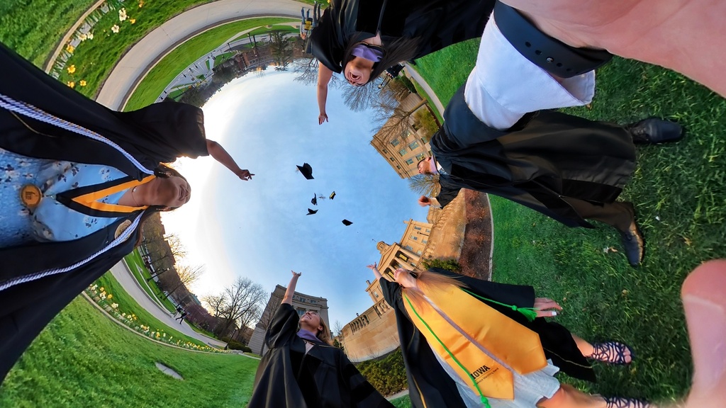 Graduates throwing caps in air from grass